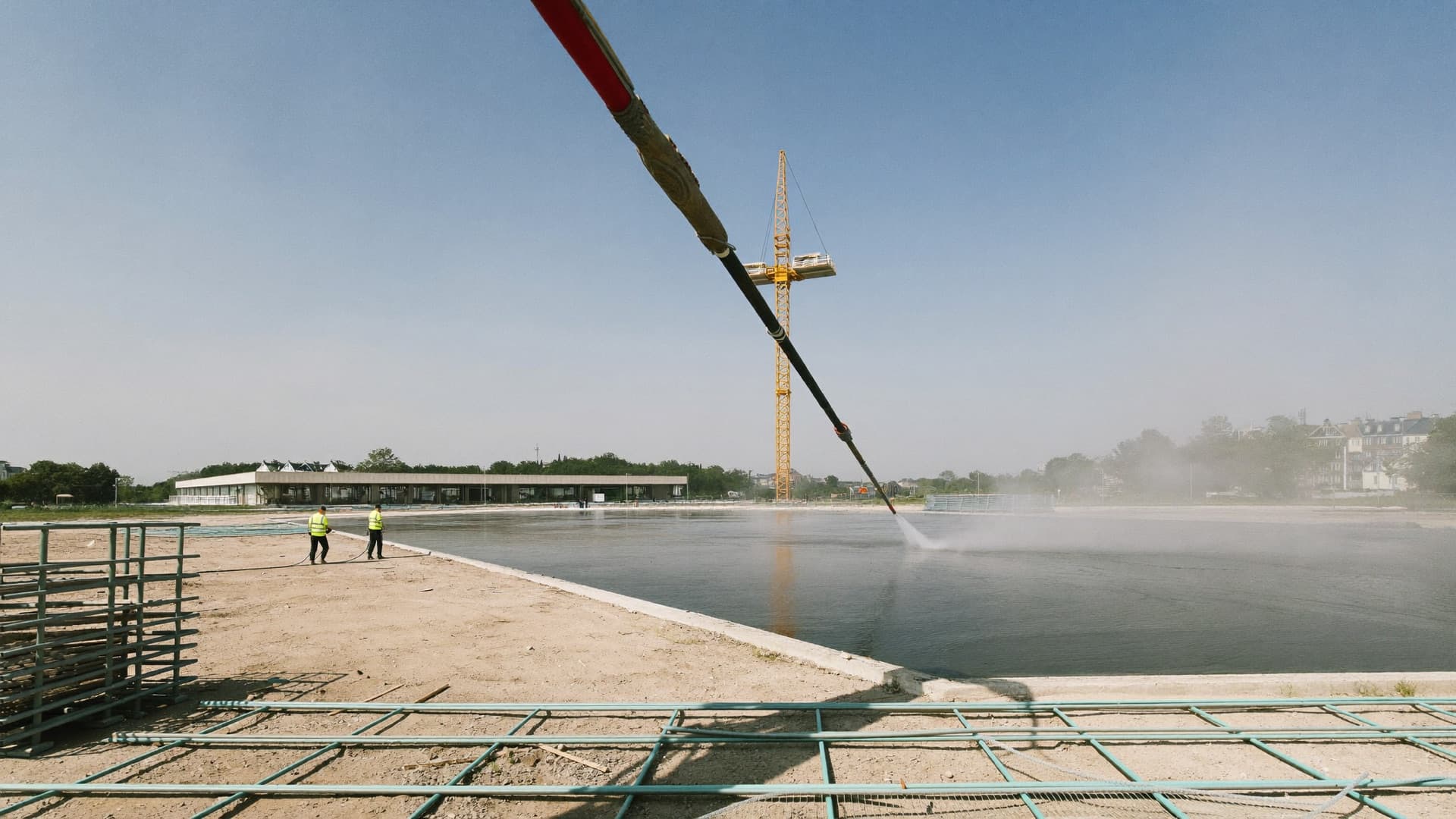 Coulage d'une dalle de béton à la pompe sur un chantier, grue à tour en arrière-plan