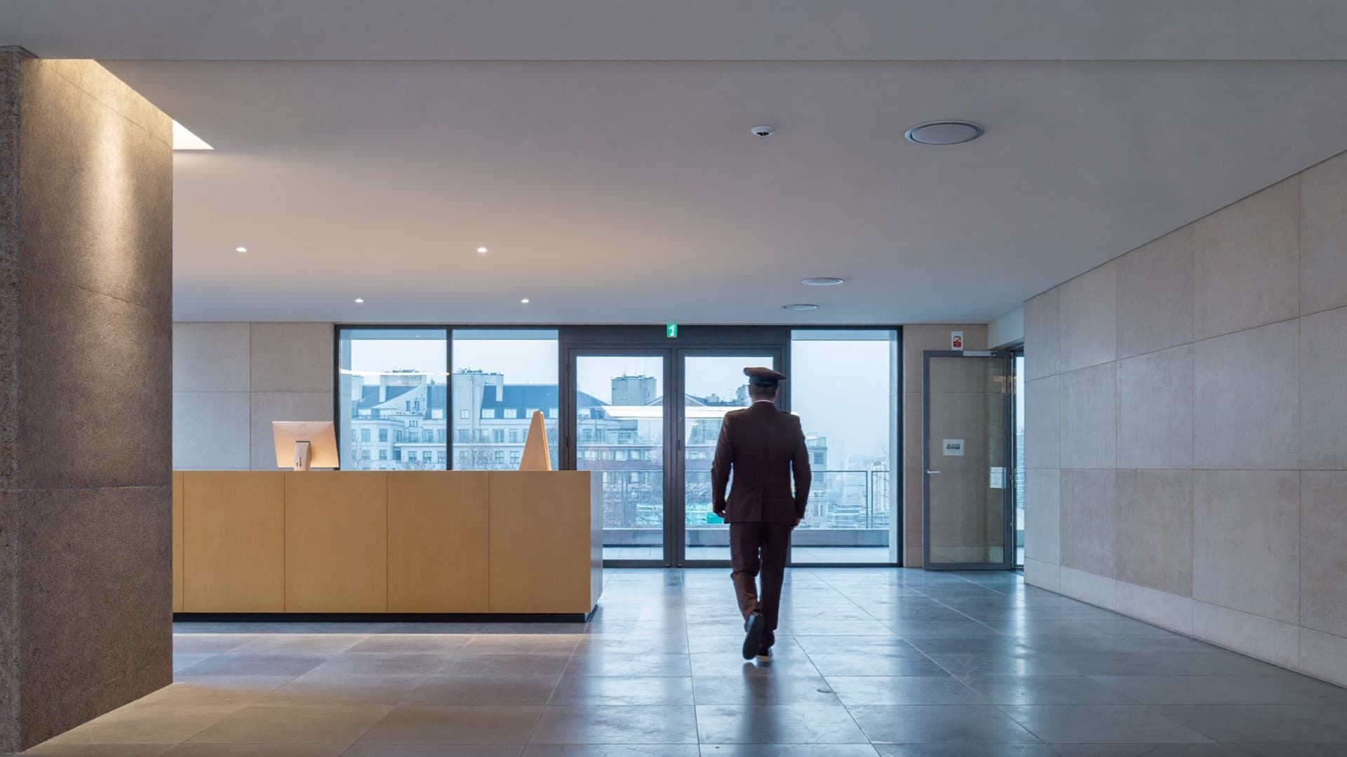 Agent de sécurité traversant le hall d'accueil d'un immeuble de bureaux au petit matin